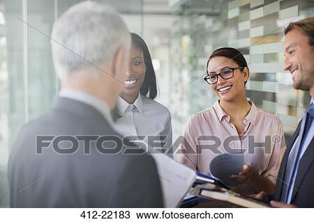 Stock Image - Business people talking in office building. Fotosearch