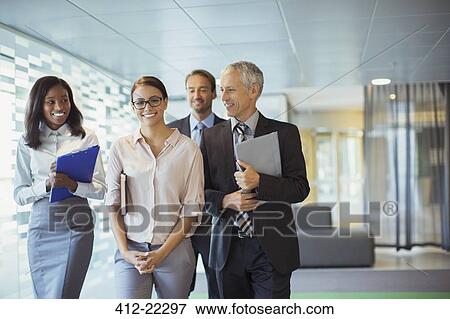 Business people walking through office building together View Large Photo Image Stock Photo - Business people walking through office building together. Fotosearch