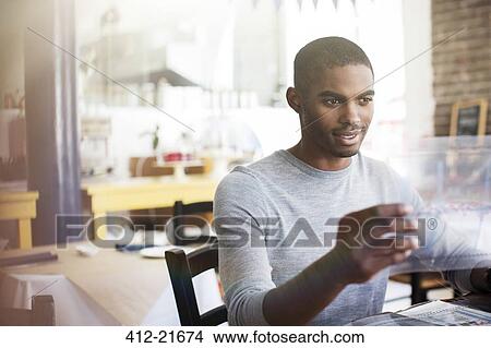 Picture - Businessman examining documents at in cafe. Fotosearch