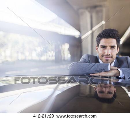 Businessman resting on car in parking garage View Large Photo Image Stock Photo - Businessman resting on car in parking garage. Fotosearch