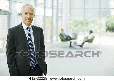 Businessman smiling in office building View Large Photo Image Stock Photo - Businessman smiling in office building. Fotosearch