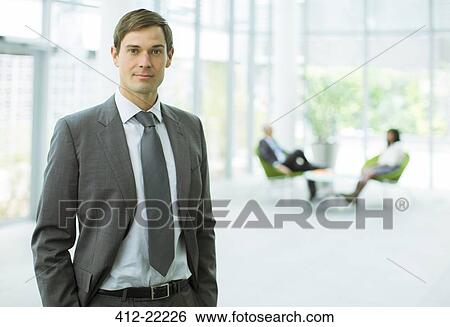 Businessman standing in office building View Large Photo Image Stock Photograph - Businessman standing in office building. Fotosearch