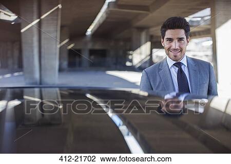 Businessman standing near car in parking garage View Large Photo Image Stock Image - Businessman standing near car in parking garage. Fotosearch