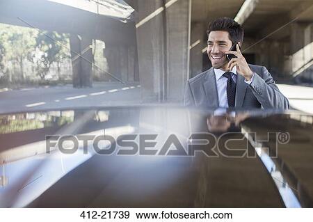 Businessman talking on cell phone in parking garage View Large Photo Image Stock Photo - Businessman talking on cell phone in parking garage. Fotosearch