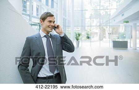 Businessman talking on cell phone in office building View Large Photo Image Stock Photography - Businessman talking on cell phone in office building. Fotosearch