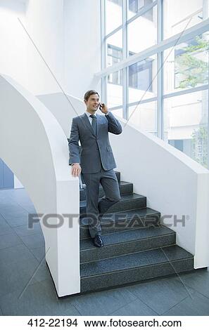 Businessman talking on cell phone walking down stairs View Large Photo Image Picture - Businessman talking on cell phone walking down stairs . Fotosearch