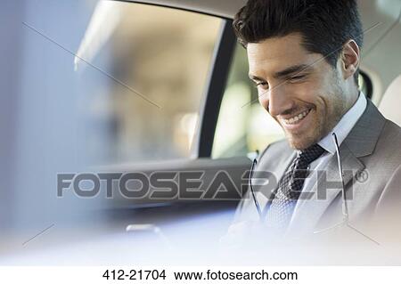 Businessman using cell phone in car back seat View Large Photo Image Picture - Businessman using cell phone in car back seat. Fotosearch