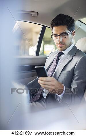 Businessman using cell phone in car back seat View Large Photo Image Stock Photo - Businessman using cell phone in car back seat. Fotosearch