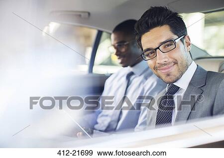 Businessman using digital tablet in car back seat View Large Photo Image Stock Photo - Businessman using digital tablet in car back seat . Fotosearch