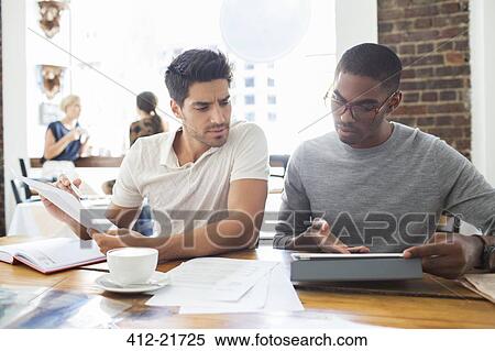 Businessmen looking at digital tablet in meeting View Large Photo Image Stock Photography - Businessmen looking at digital tablet in meeting. Fotosearch