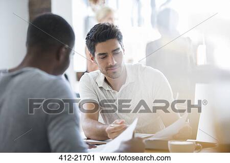 Businessmen looking through documents in cafe together View Large Photo Image Stock Image - Businessmen looking through documents in cafe together. Fotosearch