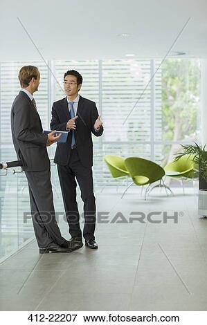 Businessmen talking in office building View Large Photo Image Stock Photo - Businessmen talking in office building. Fotosearch