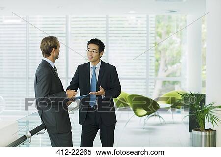Stock Photography - Businessmen talking in office building. Fotosearch