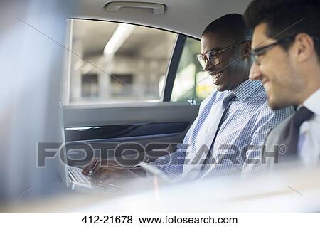 Businessmen using laptop in car View Large Photo Image Stock Photo - Businessmen using laptop in car. Fotosearch