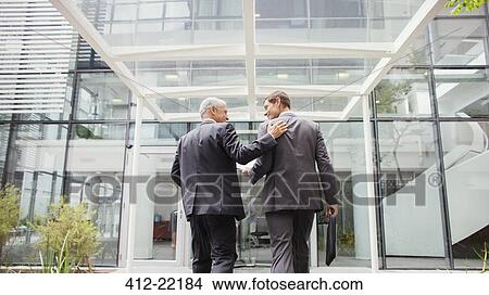 Businessmen walking into office building together View Large Photo Image Picture - Businessmen walking into office building together. Fotosearch