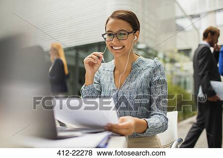 Stock Photo - Businesswoman at desk talking on headset. Fotosearch