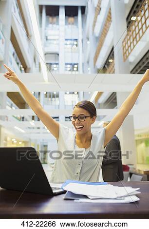 Businesswoman excited while working in office building View Large Photo Image Stock Photograph - Businesswoman excited while working in office building. Fotosearch