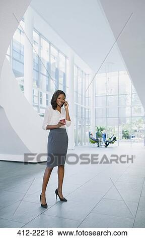 Businesswoman talking on cell phone in office building View Large Photo Image Stock Photo - Businesswoman talking on cell phone in office building. Fotosearch