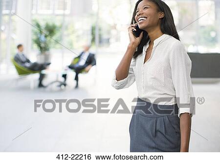 Businesswoman talking on cell phone in office building View Large Photo Image Stock Photograph - Businesswoman talking on cell phone in office building. Fotosearch