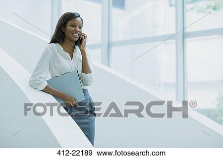 Businesswoman talking on cell phone on office building stairs View Large Photo Image Stock Photo - Businesswoman talking on cell phone on office building stairs. Fotosearch