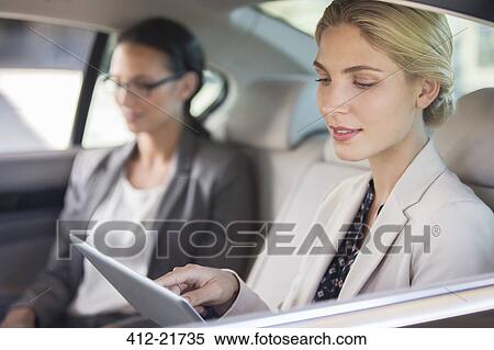 Businesswoman using digital tablet in car back seat View Large Photo Image Stock Photography - Businesswoman using digital tablet in car back seat. Fotosearch