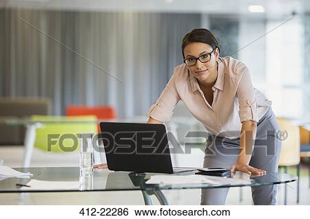 Stock Photograph - Businesswoman using laptop in office building. Fotosearch
