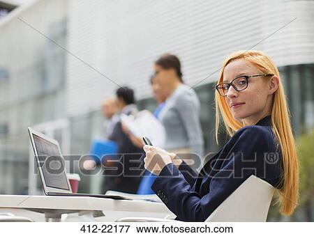 Businesswoman working at table outside of office building View Large Photo Image Stock Photo - Businesswoman working at table outside of office building. Fotosearch