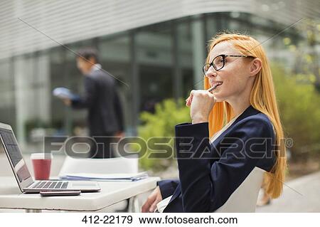 Businesswoman working at table outside of office building View Large Photo Image Stock Photo - Businesswoman working at table outside of office building. Fotosearch