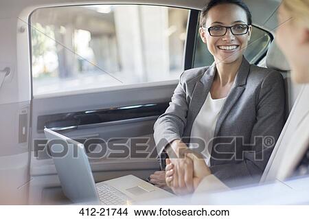 Picture - Businesswomen shaking hands in car. Fotosearch
