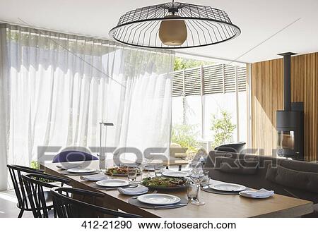 Stock Image - Chandelier over dining table in modern dining room. Fotosearch