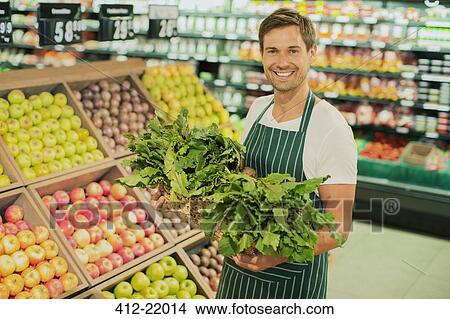 Picture - Clerk carrying produce in grocery store. Fotosearch