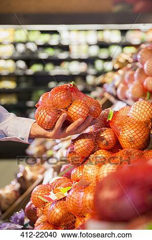 Close up of man holding bag of onions in grocery store View Large Photo Image Stock Image - Close up of man holding bag of onions in grocery store. Fotosearch