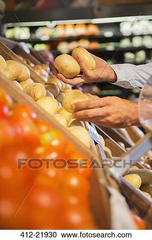 Close up of man selecting produce in grocery store View Large Photo Image Stock Image - Close up of man selecting produce in grocery store. Fotosearch
