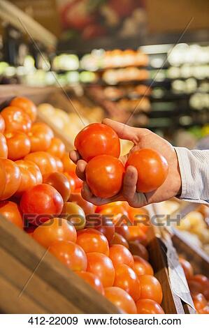 Close up of woman holding fruit in produce section of grocery store View Large Photo Image Stock Photo - Close up of woman holding fruit in produce section of grocery store. Fotosearch