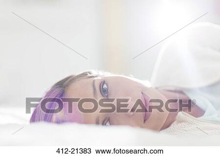 Stock Image - Close up of woman laying on bed. Fotosearch