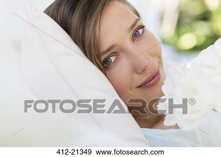 Close up of woman smelling flower on bed View Large Photo Image Stock Photo - Close up of woman smelling flower on bed. Fotosearch