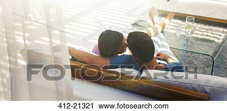 Couple relaxing together on sofa in modern living room View Large Photo Image Stock Image - Couple relaxing together on sofa in modern living room. Fotosearch