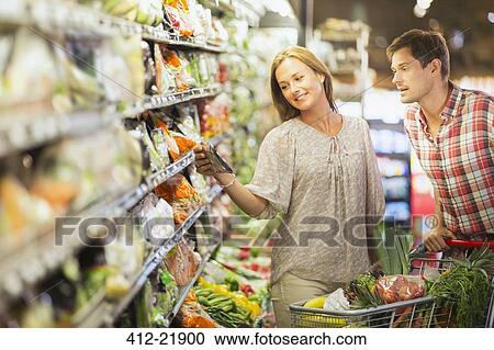 Stock Image - Couple shopping together in grocery store. Fotosearch