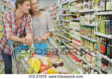 Couple shopping together in grocery store View Large Photo Image Stock Photo - Couple shopping together in grocery store. Fotosearch