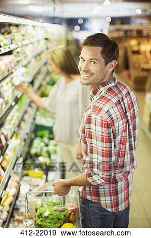Couple shopping together in grocery store View Large Photo Image Stock Photo - Couple shopping together in grocery store. Fotosearch