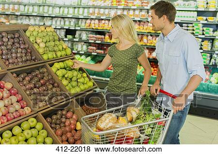 Couple shopping together in produce section of grocery store View Large Photo Image Stock Photo - Couple shopping together in produce section of grocery store. Fotosearch