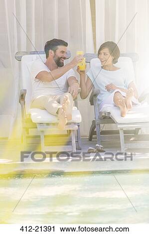Couple toasting each other in lawn chairs by swimming pool View Large Photo Image Stock Image - Couple toasting each other in lawn chairs by swimming pool. Fotosearch