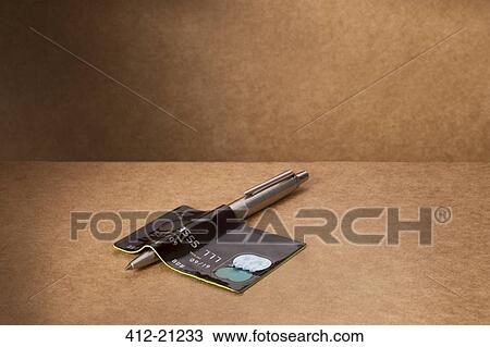Stock Image - Credit card bent over pen on counter. Fotosearch