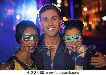 Stock Image - Friends smiling together on city street at night. Fotosearch