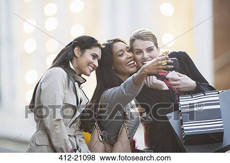 Friends talking picture with cell phone together on city street View Large Photo Image Stock Photo - Friends talking picture with cell phone together on city street . Fotosearch