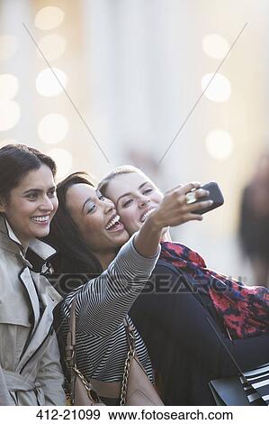Friends talking picture with cell phone together on city street View Large Photo Image Stock Photo - Friends talking picture with cell phone together on city street . Fotosearch
