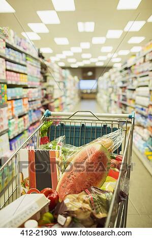 Stock Image - Full shopping cart in grocery store aisle. Fotosearch