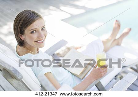 High angle view of woman reading and drinking juice by swimming pool View Large Photo Image Stock Photo - High angle view of woman reading and drinking juice by swimming pool. Fotosearch