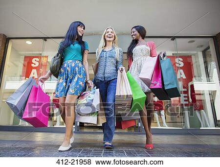 Low angle view of women carrying shopping bags outside clothing store View Large Photo Image Stock Photo - Low angle view of women carrying shopping bags outside clothing store. Fotosearch