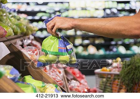 Man holding bag of produce in grocery store View Large Photo Image Stock Image - Man holding bag of produce in grocery store. Fotosearch